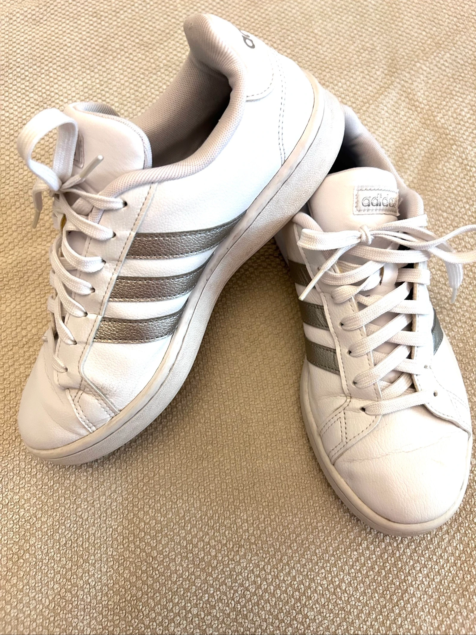 Zapatillas Adidas Grand Court en color blanco con las tres bandas plateadas metalizada